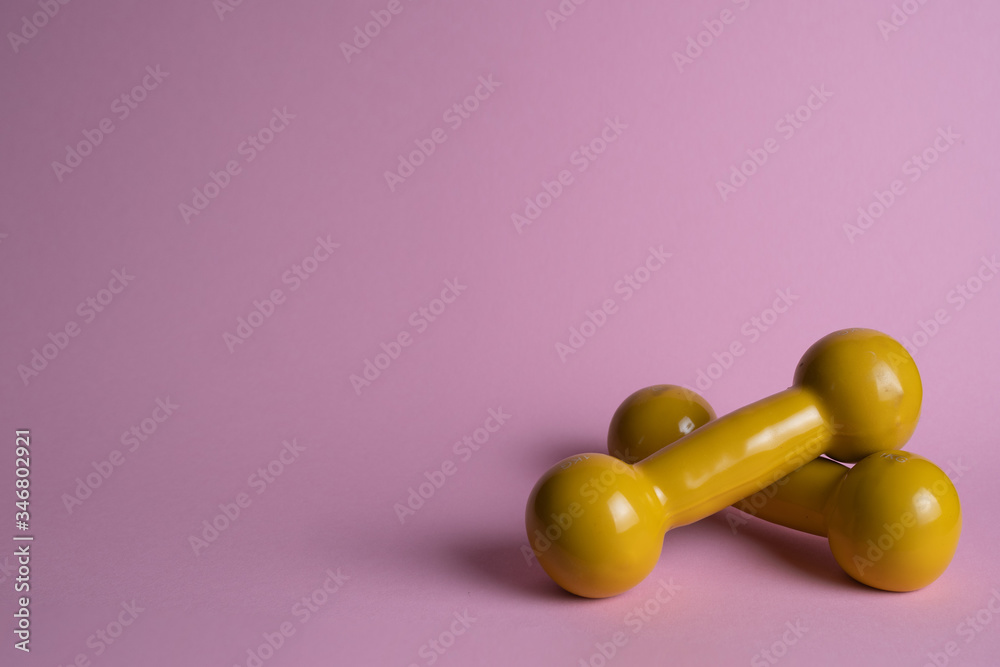 yellow dumbbells on a pink background yellow dumbbells on a pink background