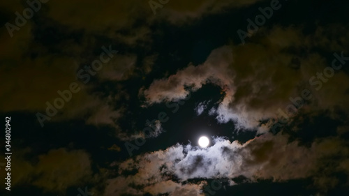 the moon shines brightly through the clouds in the night sky © orlovphoto