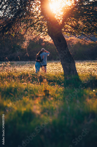 Couple in love standing together on colorful meadow in beautiful sunset light.