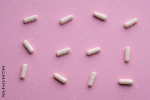 A lot of white pills on a pink background.