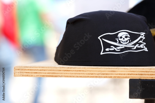 cappello da pirata con classico teschio e spade sopra tavolo di compensato photo