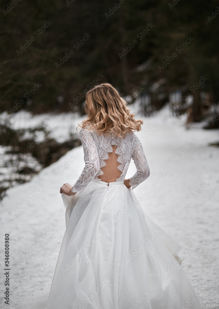 bride with blonde hair running away from wedding in white traditional dress with open back during winter bride with blonde hair running away from wedding in white traditional dress with open back during winter