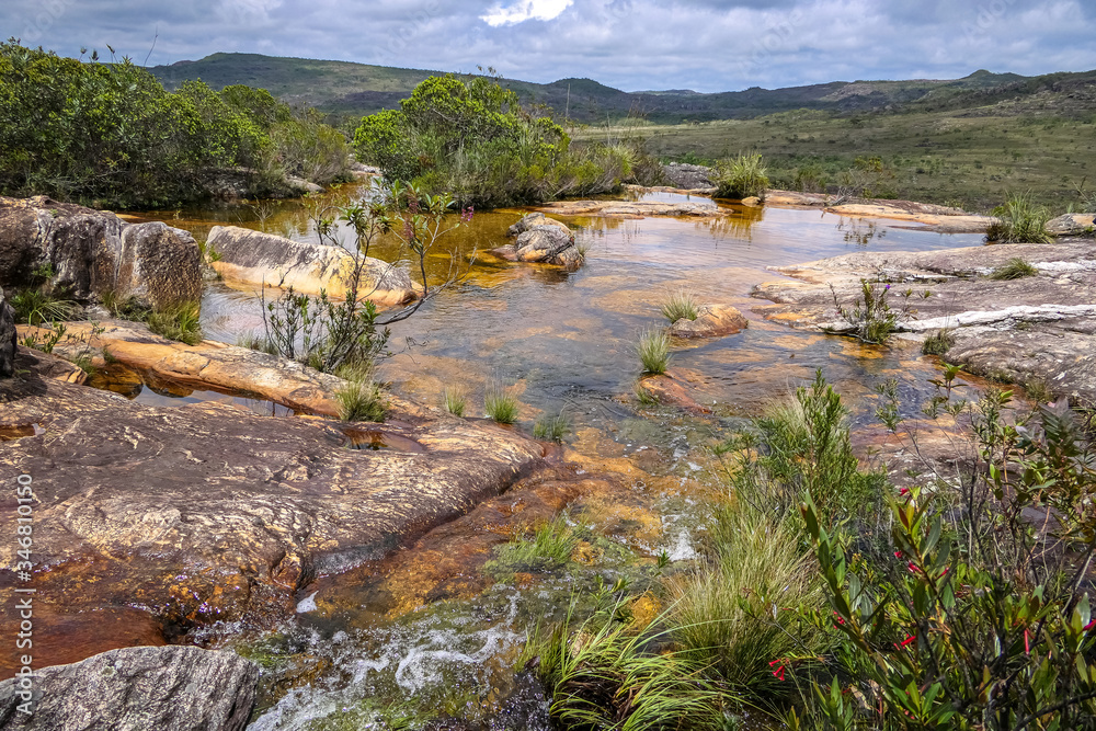 Rocky shallow riverbed above a waterfall with blooming scrubs and view, Biribiri State Park, Minas Gerais, Brazil Rocky shallow riverbed above a waterfall with blooming scrubs and view, Biribiri State Park, Minas Gerais, Brazil