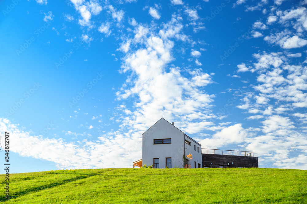 Obraz premium Modern house on green meadow. Blue sky, edit space. Architecture photo.