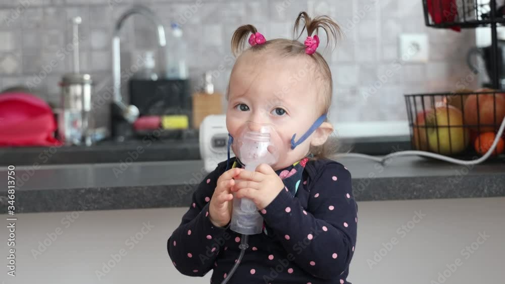 Cute little baby in the mask of an inhaler. Procedure of inhalation at home. Baby taking respiratory therapy with nebulizer. Cute little baby in the mask of an inhaler. Procedure of inhalation at home. Baby taking respiratory therapy with nebulizer.