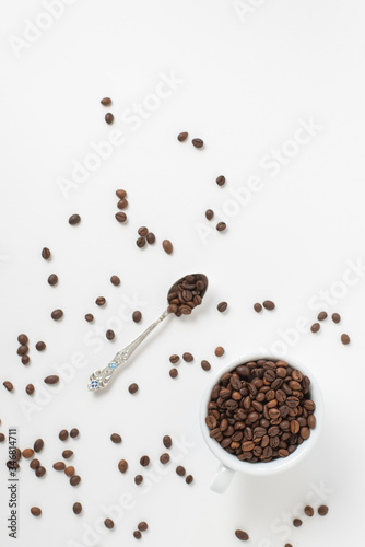 Cup оf coffee , white ceramic cup with roasted coffee beans and a teaspoon on a white background. Isolate. Space for text. Top view