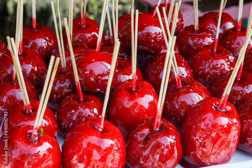 Sweet glazed red toffee candy apples on sticks for sale on farmer market or country fair.