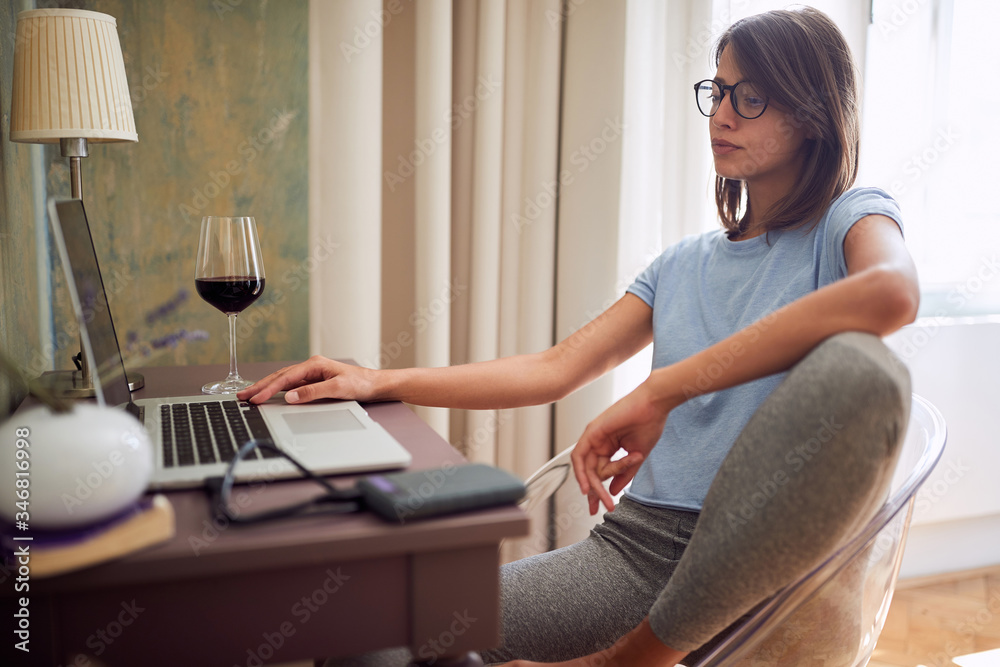 young adult caucasian female sitting at desk in front of laptop, thinking young adult caucasian female sitting at desk in front of laptop, thinking