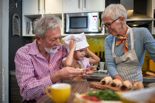 grandparents with their granddaughter between them with a cook hat