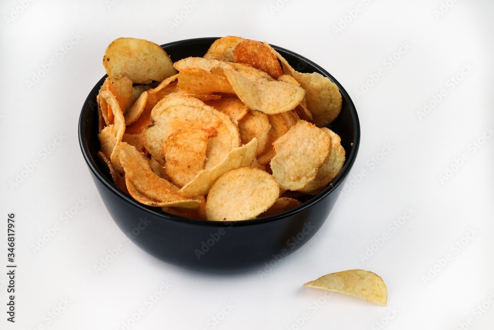 potato chips in a black bowl on a white background potato chips in a black bowl on a white background