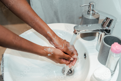 Cropped view of african american woman washing hands in bathroom