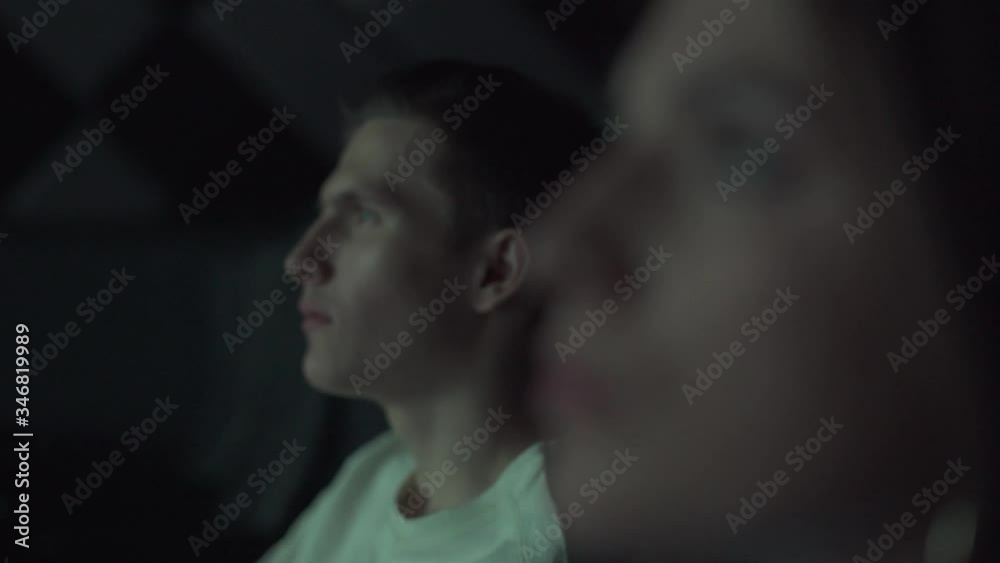 Portrait of a Young couple in a movie theater, watching a movie on a big screen, a date, the effect of glowing light. Portrait of a Young couple in a movie theater, watching a movie on a big screen, a date, the effect of glowing light.