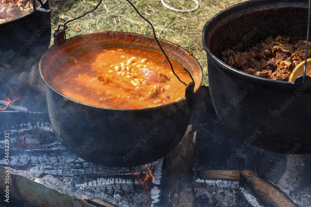 Very large cauldron cooking food during campfire. Cooking in a pot on the fire. Camping concept Very large cauldron cooking food during campfire. Cooking in a pot on the fire. Camping concept
