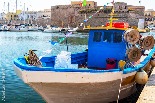 Empty moored fishing tourism boat at the Port of Gallipoli, Province of Lecce, Apulia, Italy, the Castle of Gallipoli in the background