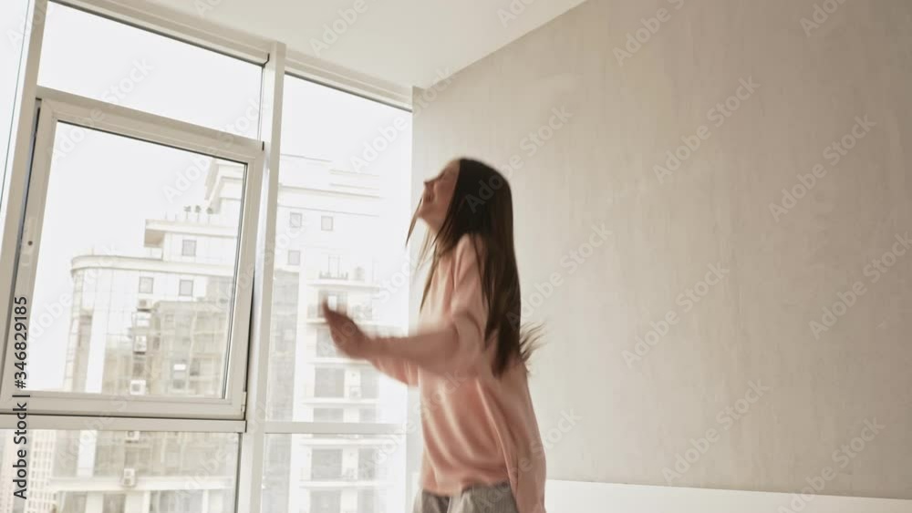 A happy cheerful girl is jumping on the bed at home in the morning A happy cheerful girl is jumping on the bed at home in the morning
