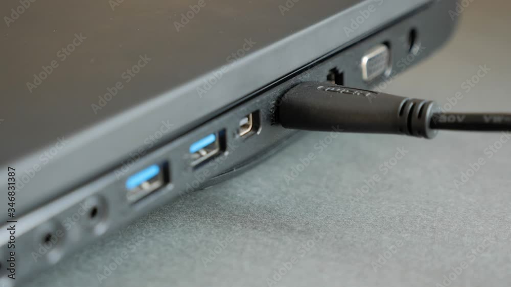 Inserting HDMI cable into the side port of a laptop computer. HDMI