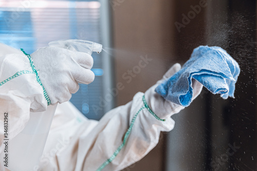 Coronavirus Pandemic. A disinfector in a protective suit and mask sprays disinfectants in house or office. Protection against COVID-19 disease. Prevention of spreding pneumonia virus with surfaces.