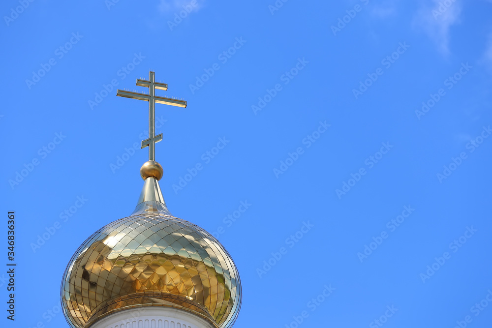 Close-up of the Orthodox golden cross on the roof of the Church against the background of blue sky