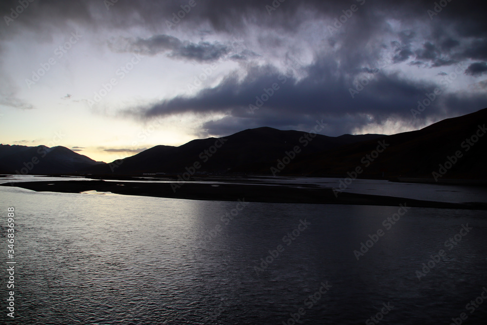 The dark mountains and the quiet lake in the sunset The dark mountains and the quiet lake in the sunset