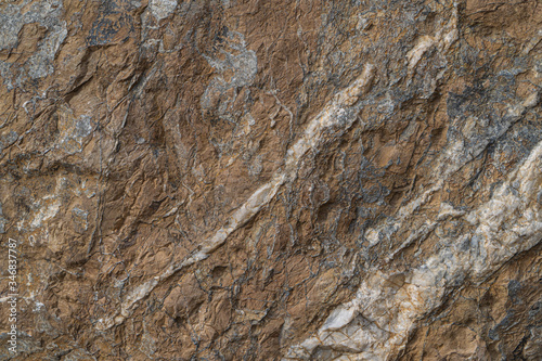 Gold ore texture close-up. Contains quartz, mica, feldspar, chlorite, garnet, carbonate, sulfides and gold. Siberian natural resources deposit. Mineral stone surface abstract background.