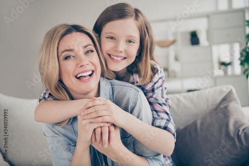 Closeup photo of domestic attractive blond lady mommy daughter sitting comfy couch hugging piggyback stay home quarantine spend weekend together best friends living room indoors