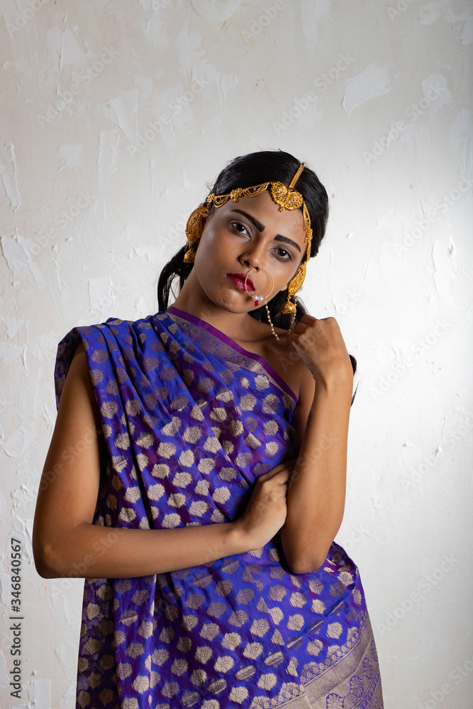 Fototapeta premium Indian girl wearing a traditional blue saree and gold jewellry