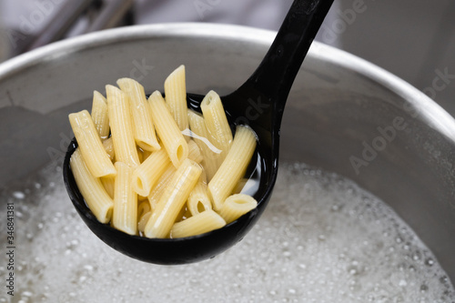 Boiled penne on a ladle