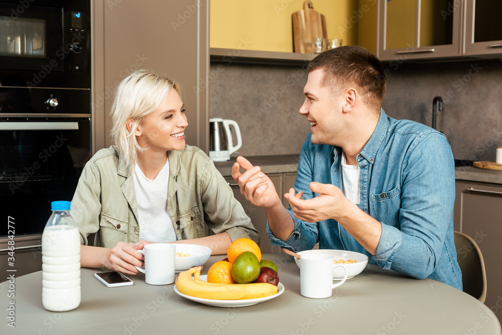 smiling couple talking while having breakfast in kitchen smiling couple talking while having breakfast in kitchen