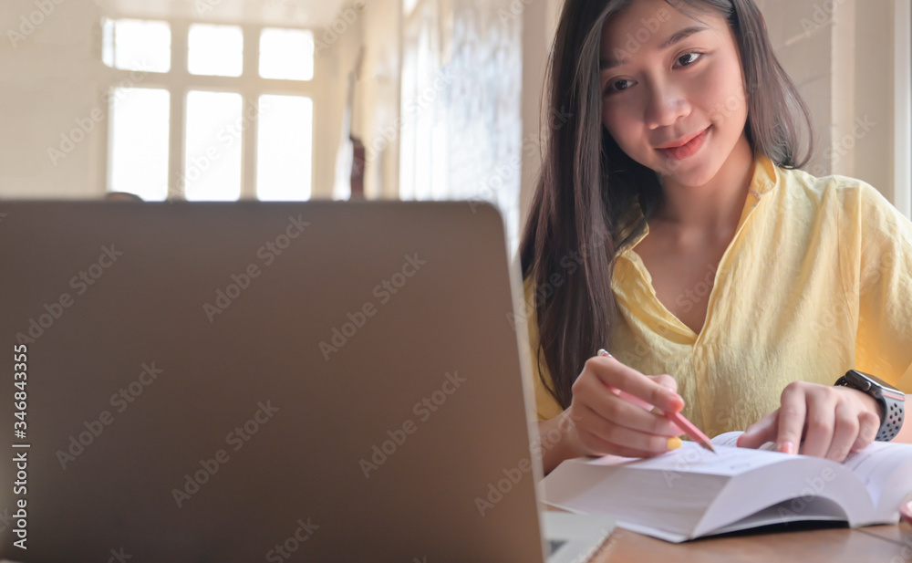 Asian teenage female student search for information from laptop and take notes. She prepares for university entrance exam. Asian teenage female student search for information from laptop and take notes. She prepares for university entrance exam.