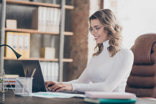Close-up portrait of nice attractive focused cheerful wavy-haired girl marketer ceo boss chief founder typing partner email in modern loft brick industrial interior style workplace workstation