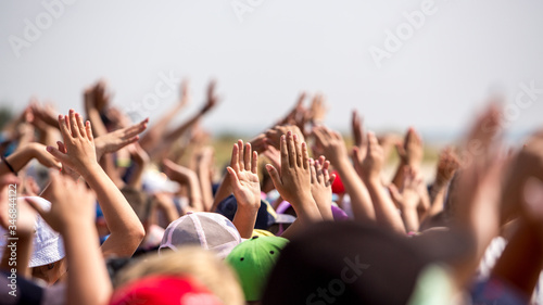 group of happy young people with hands up to the sky