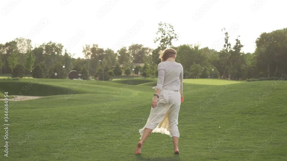 Beautiful girl in a white dress is dancing in nature. Wind develops hair Beautiful girl in a white dress is dancing in nature. Wind develops hair