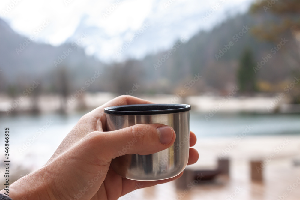 male hand keep thermos cup walking outdoors