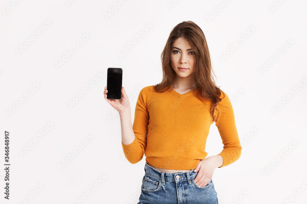 A young girl is holding a smartphone. Portrait of a girl with a phone in her hands on a light background with space for text A young girl is holding a smartphone. Portrait of a girl with a phone in her hands on a light background with space for text