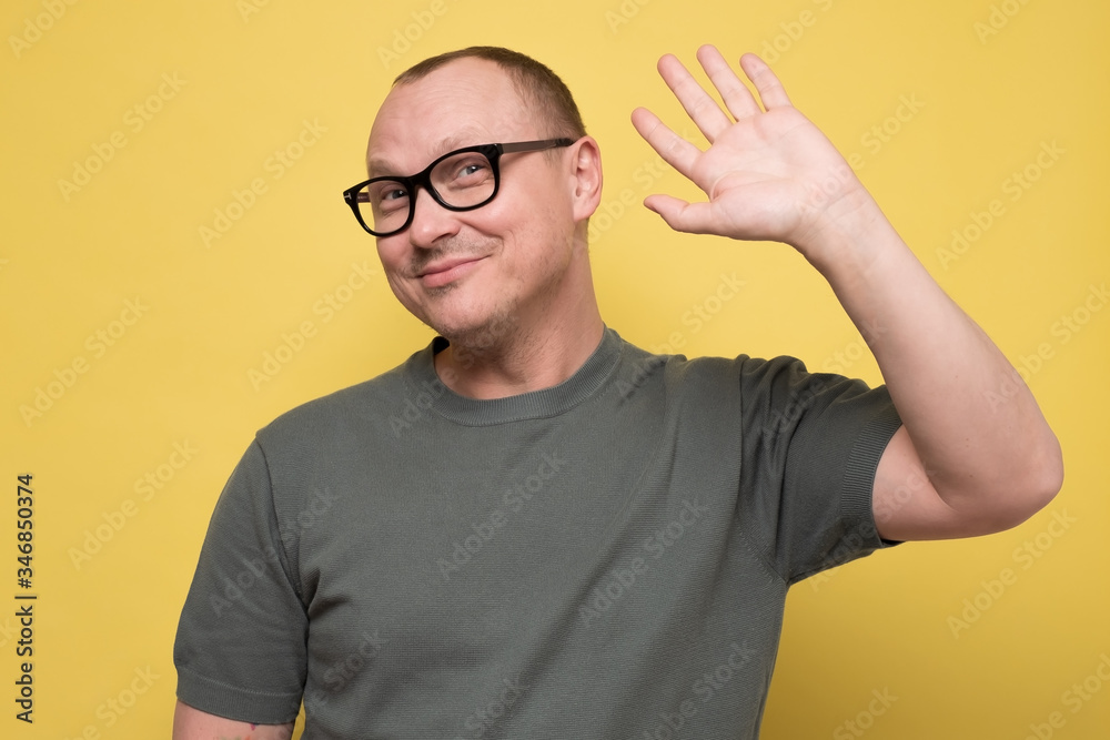 Naklejka premium Friendly looking polite mature man saying hi, waving with his hand
