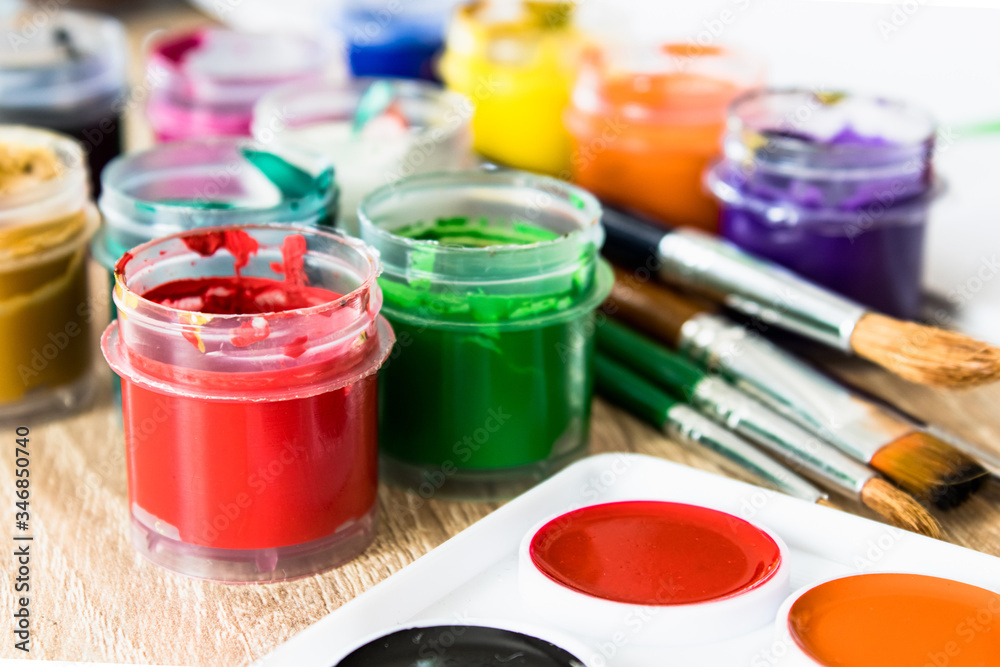 On the table are watercolor paints, brushes and gouache paints. Set for drawing, creativity and hobbies. On the table are watercolor paints, brushes and gouache paints. Set for drawing, creativity and hobbies.