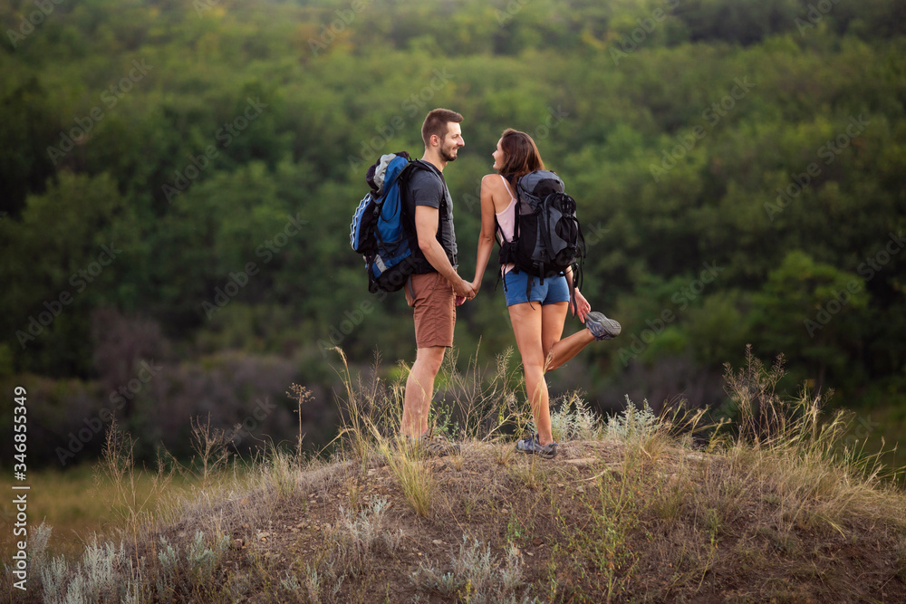 A man and a woman are hiking in the mountains with backpacks.