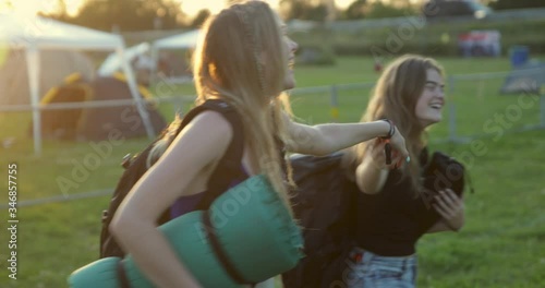Happy departing caucasian girls hugging in slow motion at festival camping site in sunny backlight and flare