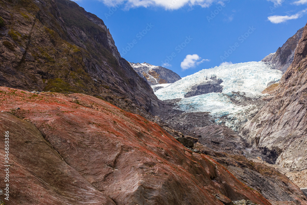 Red boulder on a background of a glacier. View of Franz Joseph Glacier in New Zealand