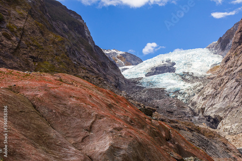 Red boulder on a background of a glacier. View of Franz Joseph Glacier in New Zealand