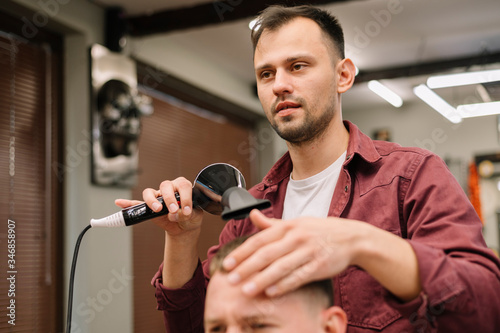 Front view of male hairdresser using the hair dryer