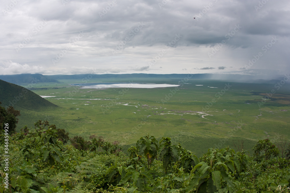 Ngorongoro caldera panoramic crater view wet season storm rain over green grass plain 