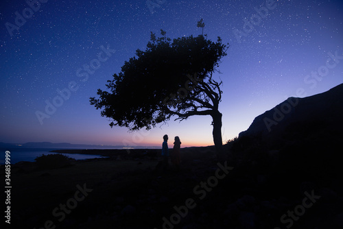 Silhouette of couple with night scene milky way background in the galaxy. under tree. Romantic star night shot photo