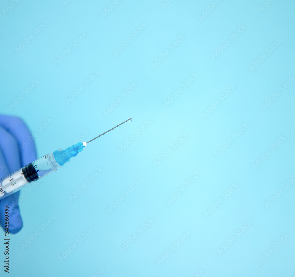 The doctor holds a syringe. Injection with medication. Medical worker in blue gloves. Vaccine in a syringe. Cosmetic procedures. The nurse will give an injection The doctor holds a syringe. Injection with medication. Medical worker in blue gloves. Vaccine in a syringe. Cosmetic procedures. The nurse will give an injection