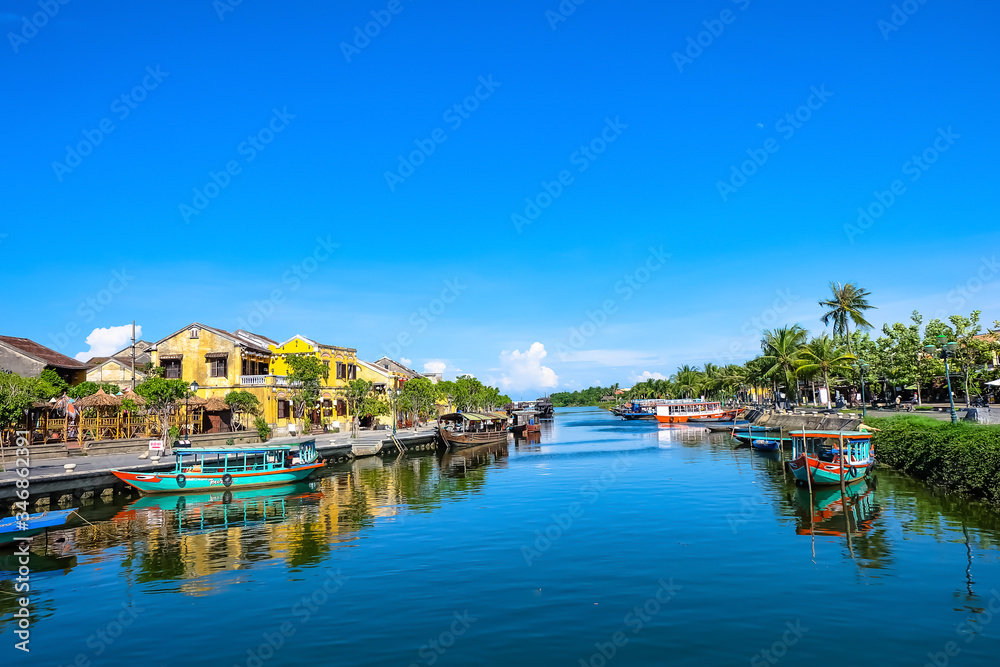Hoi An ancient town in the sunshine day with blue sky, fishing boats, ancient houses reflect on the river. Hoi An is a popular tourist destination in Quang Nam, Vietnam. Landscape photography.