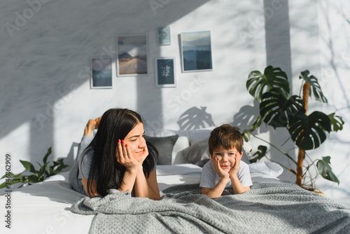 Portrait of a happy mother and her children son lying on a bed
