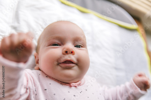 Newborn baby two-months-old smiles and lies on a white blanket. Psychomotor development and baby care photo