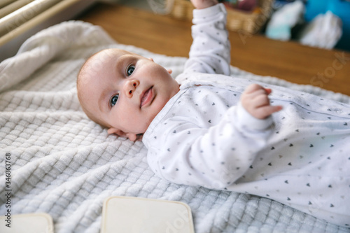 Newborn baby two-months-old smiles and lies on a white blanket. Psychomotor development and baby care photo