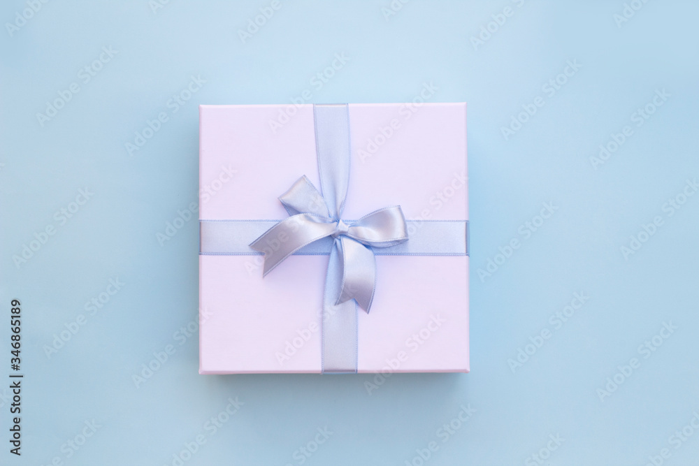 Top view of white gift box with blue ribbon on blue background Top view of white gift box with blue ribbon on blue background