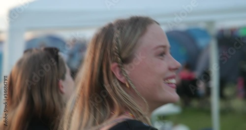 Smiling caucasian girls walking at festival camping site in slow motion 